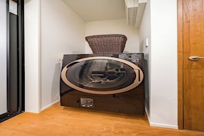 A compact, modern laundry room with a built-in washer and dryer, a wicker basket on top of the dryer, and a wooden floor. - 3-bedroom Designer accommodation OE for 6 people / 8 minutes from Shinjuku (Setagaya City)