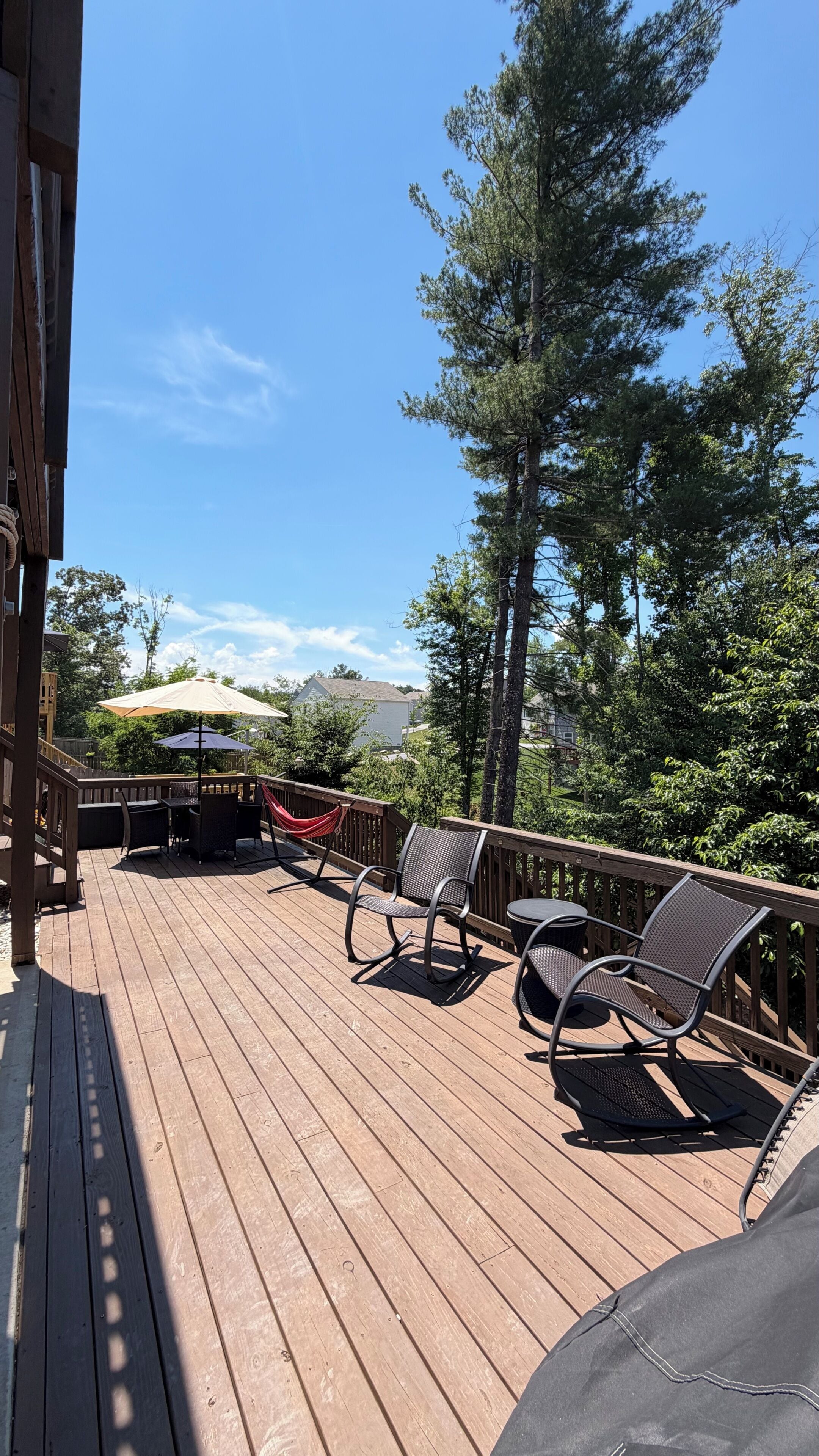 Una terraza de madera con mobiliario exterior y vistas a una zona boscosa.