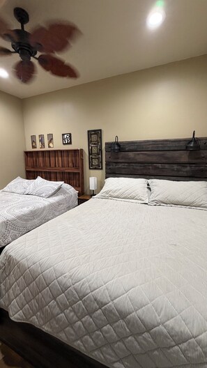 A bedroom with two beds, a ceiling fan, and a wooden headboard. - Cozy private space with an outdoor patio, 10 minutes from downtown Asheville (Candler)