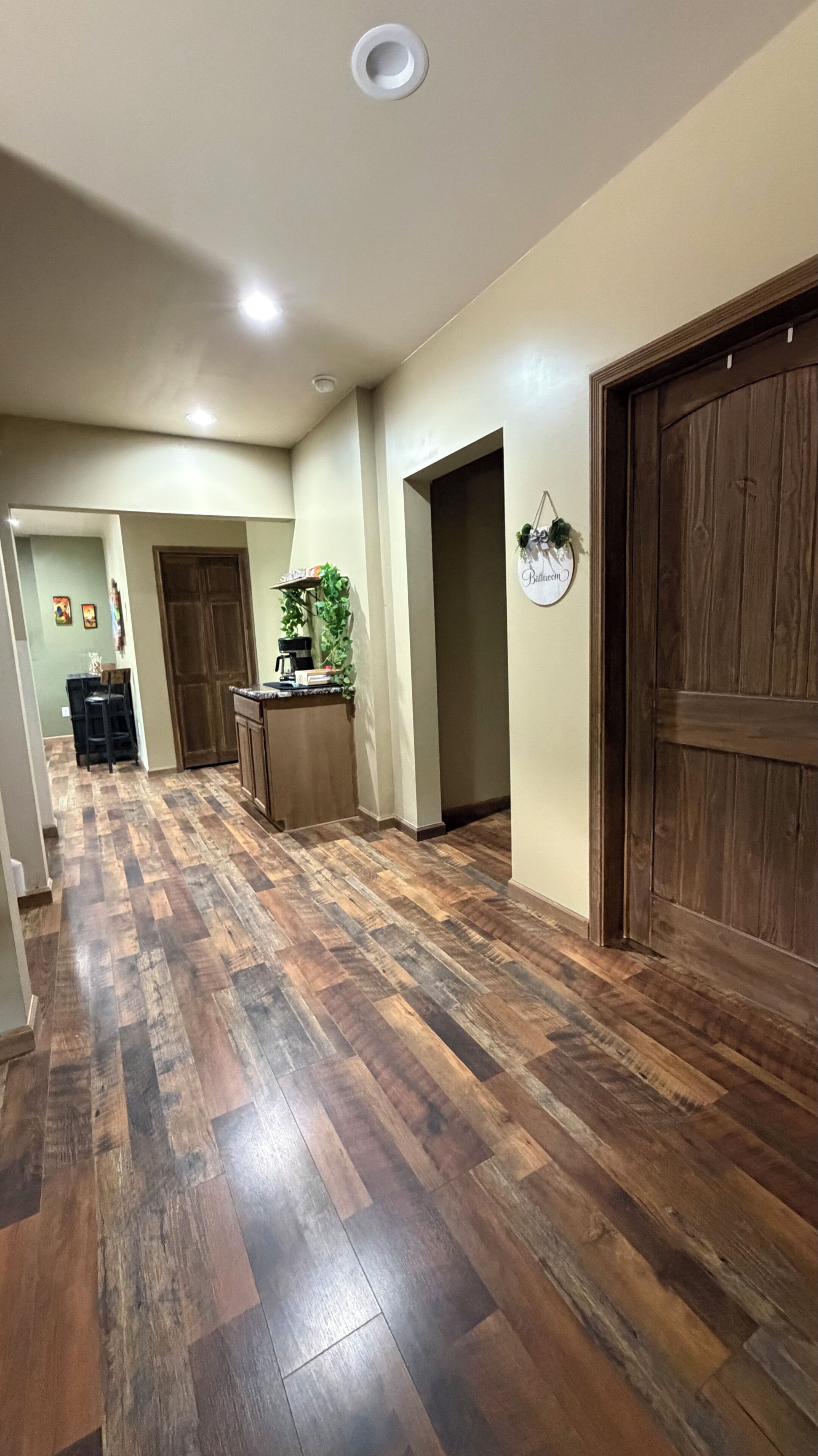 Un couloir avec un plancher en bois, une machine à café et un panneau accroché au mur.