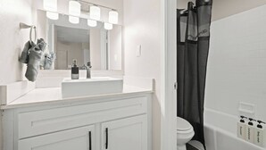 A bathroom with a white sink, mirror, and a shower curtain. - Zilker Park Studio | Near Barton Springs &Downtown (Austin)