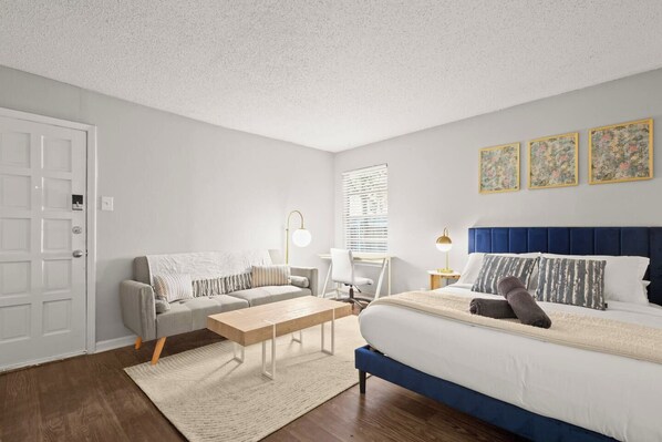 Ein Schlafzimmer mit einem Bett, einem Schlafsofa, einem Schreibtisch und einem Sessel.