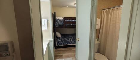 A narrow hallway leading to a bathroom with a toilet and shower curtain.