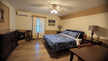 Un dormitorio con cama, cómoda, mesita de noche, lámpara y ventilador de techo.