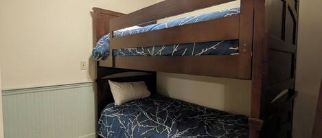 A bunk bed with a blue patterned bedspread and a white pillow.