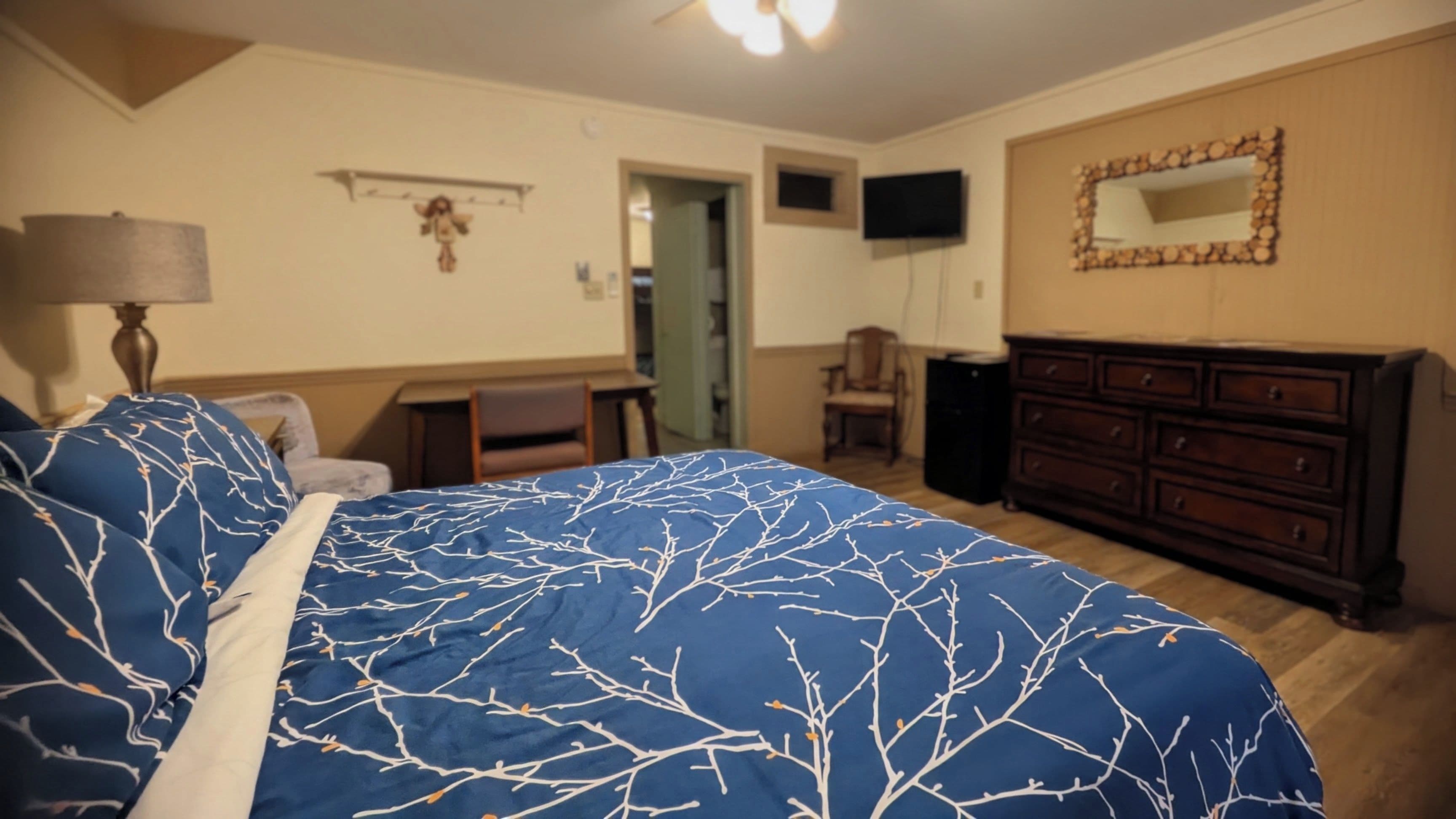 Ein Schlafzimmer mit Bett, Kommode, Fernseher und Stuhl.