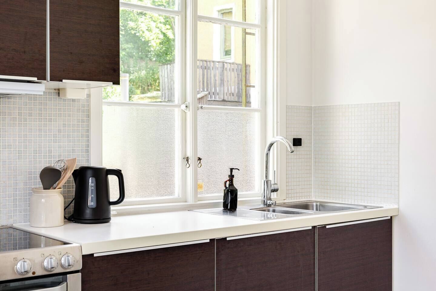 Eine Küche mit einer doppelten Spüle, einer Kaffeemaschine und einer Handseifenflasche.