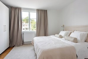 A bedroom with a bed, curtains, a radiator, and a window.