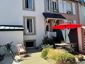 A courtyard with a bicycle, a striped beach chair, a red umbrella, and a table with chairs. - Charming 3-bedroom house in Quimper perfect for relaxing stays (Quimper)