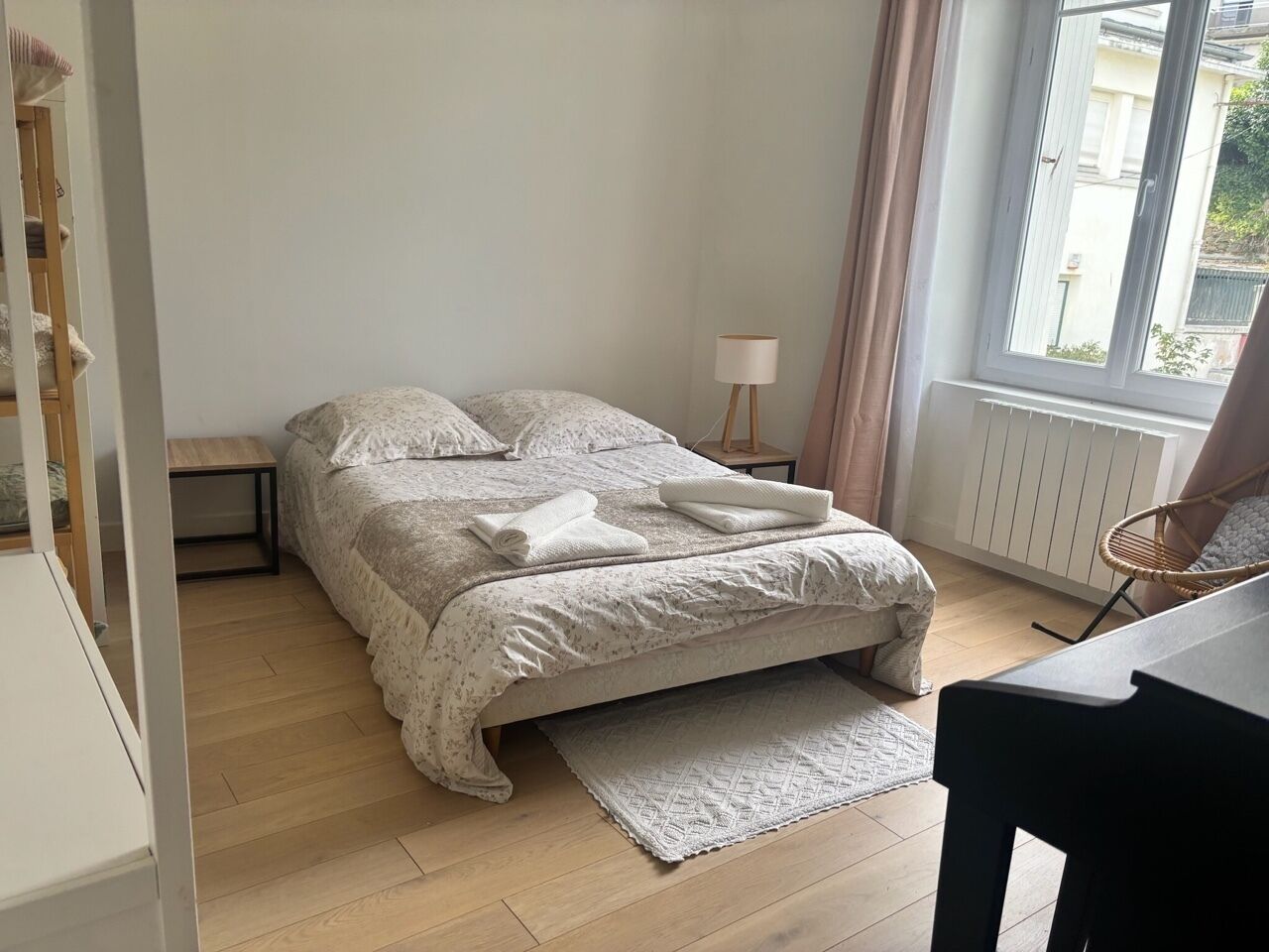 Een slaapkamer met een bed, nachtkastje, lamp en uitzicht.