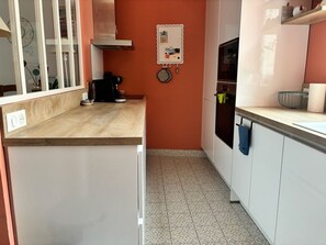 A kitchen with white cabinets, a wooden countertop, and a patterned tile floor. - Charming 3-bedroom house in Quimper perfect for relaxing stays (Quimper)