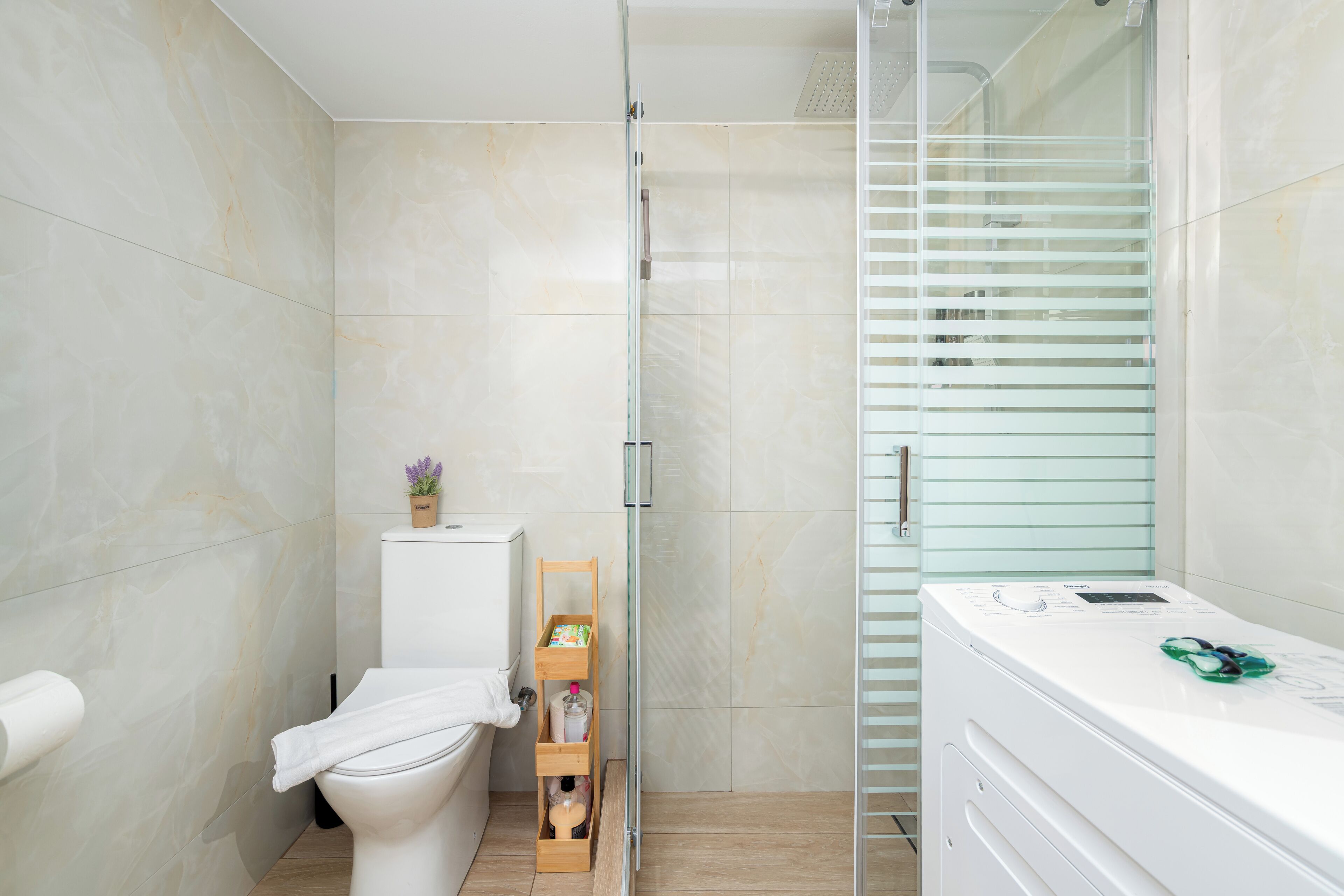 Ein modernes Badezimmer mit Toilette, einer Duschkabine aus Glas und einer Waschmaschine.