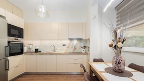 A modern kitchen with built-in appliances, a dining area with a table and chairs, and a decorative vase. - Modern Kallithea flat - Metro-AC-WiFI (Kallithea)