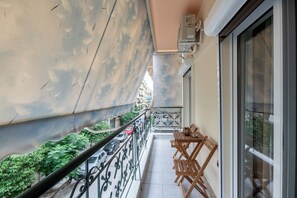 Ein Balkon mit Metallgeländer, einem Tisch mit Stühlen und Blick auf die Straße darunter.