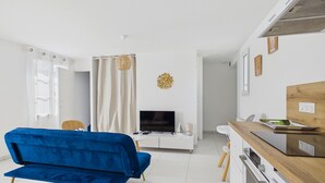 Ein modernes Wohnzimmer mit einem blauen Sofa, einem Fernseher und einer Küchenzeile mit einer Holzarbeitsplatte.
