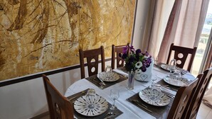 Een eettafel gedekt met borden, bestek en een bloevas.