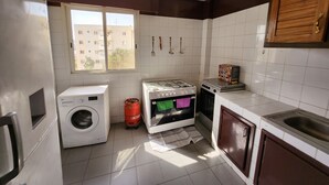 Een kleine keuken met een wasmachine, een gasfornuis en een kleine oven.
