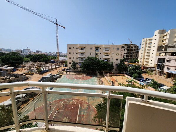 A view from a balcony overlooking a basketball court, a construction crane, and a multi-story residential building. - Residence Cité Gorgui (Dakar)