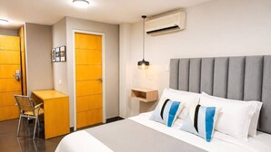 A hotel room with a large bed, a desk, a chair, and a wardrobe. - Hotel Centro (Cali)