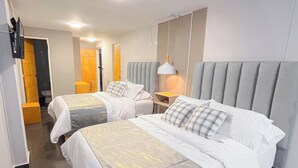 A hotel room with two beds, a bathroom, and a small sitting area. - Hotel Centro (Cali)