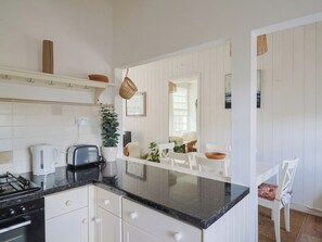 A kitchen with white cabinetry, a black countertop, a gas stove, a toaster, and a coffee maker. - 1 The Old Posthouse (Lyme Regis)