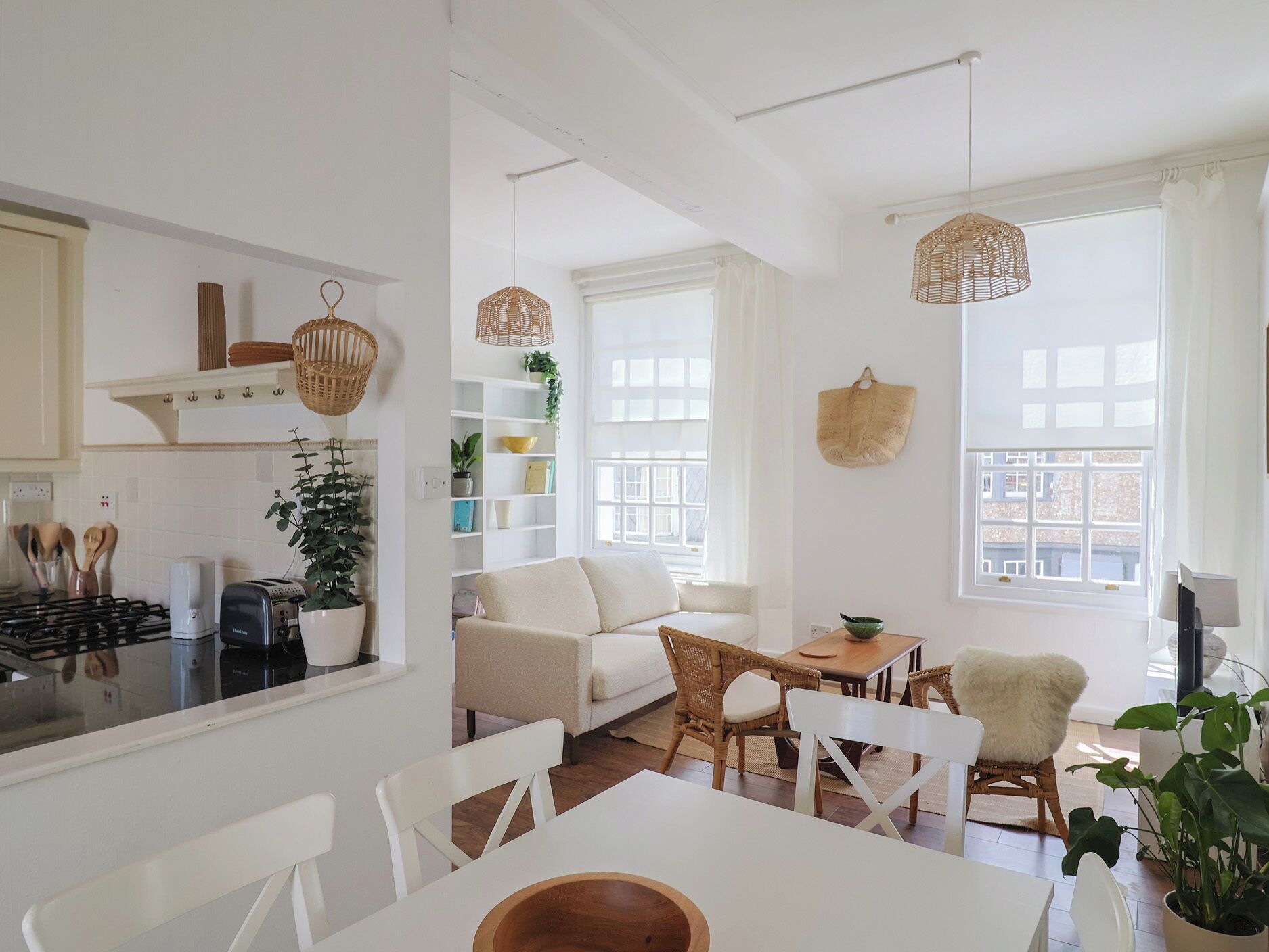 Una cocina moderna con armarios blancos, una estufa y un comedor con mesa y sillas blancas.