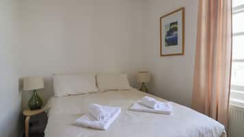 Una camera d'albergo con un letto grande, due comodini con lampade, un quadro appeso alla parete e una finestra con tende.