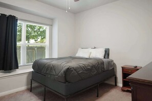 A bedroom with a bed, a nightstand, a window with curtains, and a ceiling fan. - Modern 2BR Haven near Austin & Tesla (Manor)
