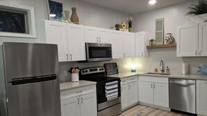 A modern kitchen with white cabinets, stainless steel appliances, and a built-in microwave.
