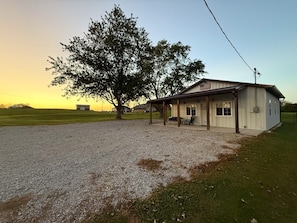 A single-story building with a covered porch, a small attached garage, and a gravel driveway.