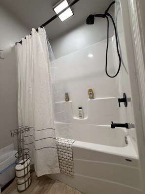 A modern bathroom with a bathtub, a shower, and a towel rack.
