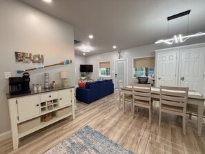 A modern living room with a sofa, coffee table, and a dining area with a table and chairs.