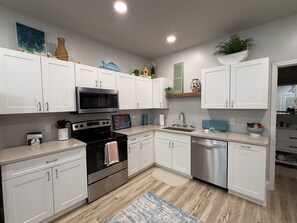 A modern kitchen with white cabinets, stainless steel appliances, and a wooden floor. - The Last Lake Stop- 2Bedroom Home (Peru)