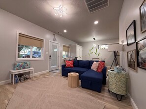 A modern living room with a sectional sofa, a small round coffee table, and a bench with a colorful cushion. - The Last Lake Stop- 2Bedroom Home (Peru)