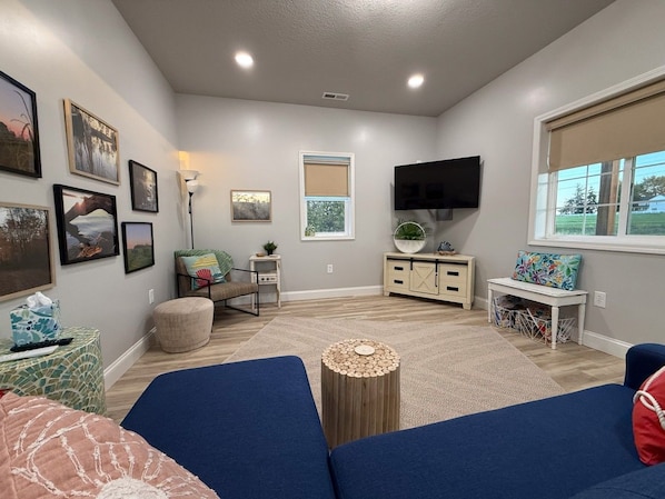 A living room with a flat-screen TV, a sofa, a coffee table, and a window with a view.