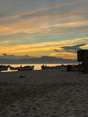 A beach with boats and a wooden structure. - Canto das Borboletas (Florianópolis)