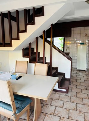 A dining area with a table, chairs, and a staircase leading to a kitchen area.