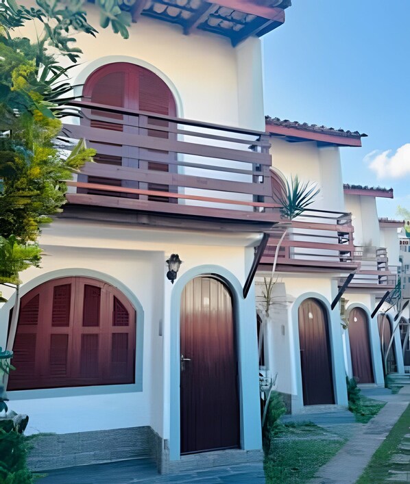 A two-story building with a balcony, arched windows, and a pathway leading to the entrance.