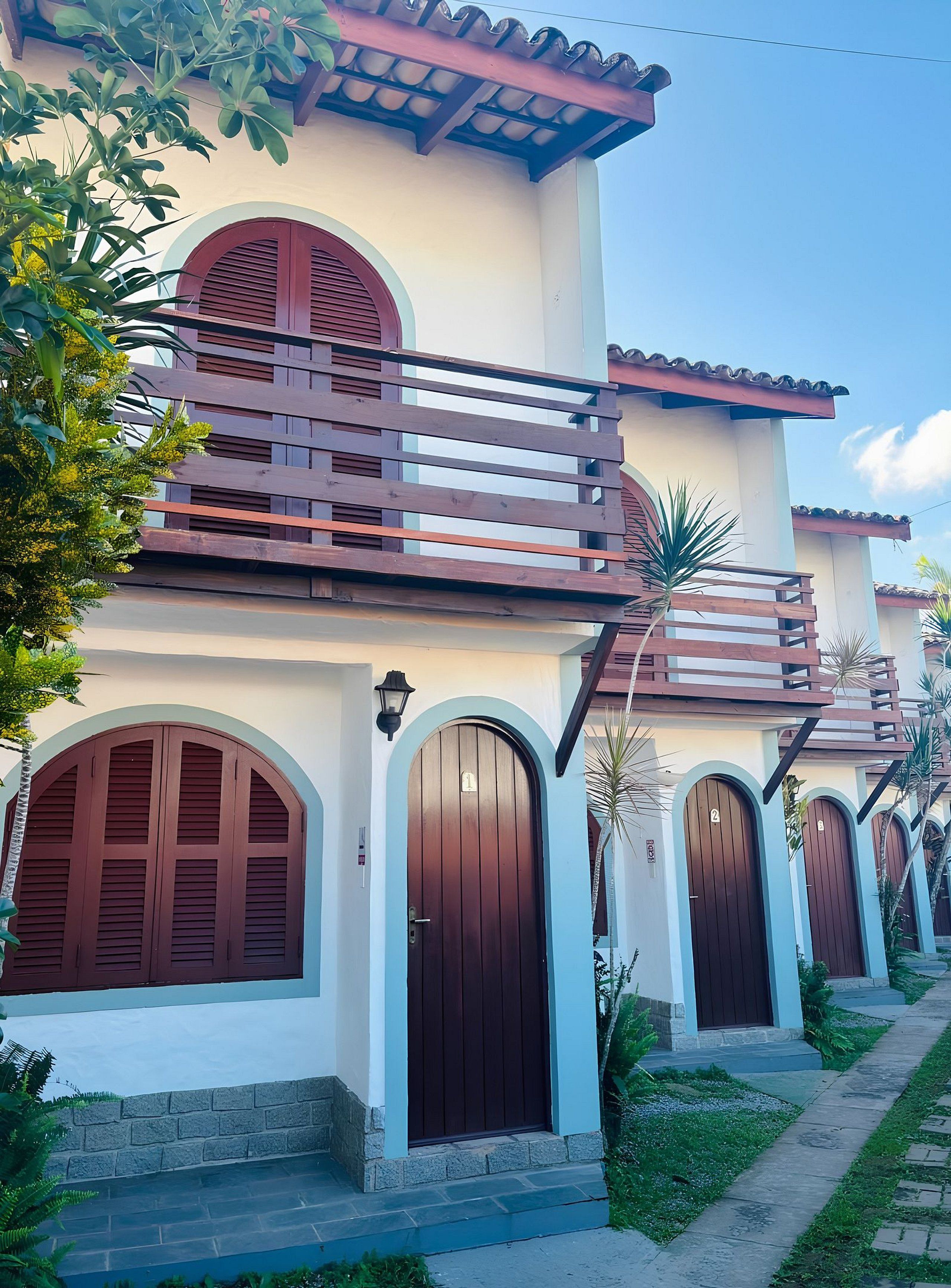 A building with multiple arched doors and a balcony with wooden railings.