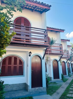 A building with multiple arched doors and a balcony with wooden railings.