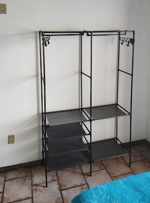 A metal shelving unit with three shelves against a white wall, next to a tiled floor. - Canto das Borboletas (FlorianĂłpolis)