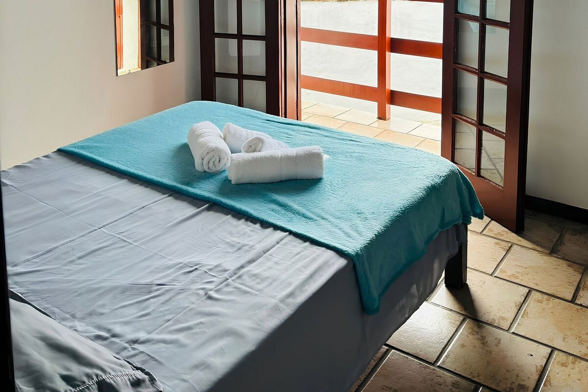 A room with a bed, an air conditioning unit, a window, and a view of the outside.