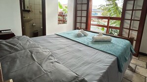 Ein Zimmer mit Bett, Fenster und Blick auf Grünfläche.