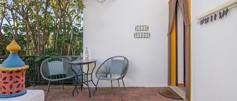 An outdoor patio with two chairs and a table, a decorative lamp, and a wall-mounted sign.