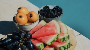 A fruit platter with grapes, watermelon slices, and blackberries by a pool.