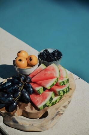 A fruit platter with grapes, watermelon slices, and blackberries by a pool.