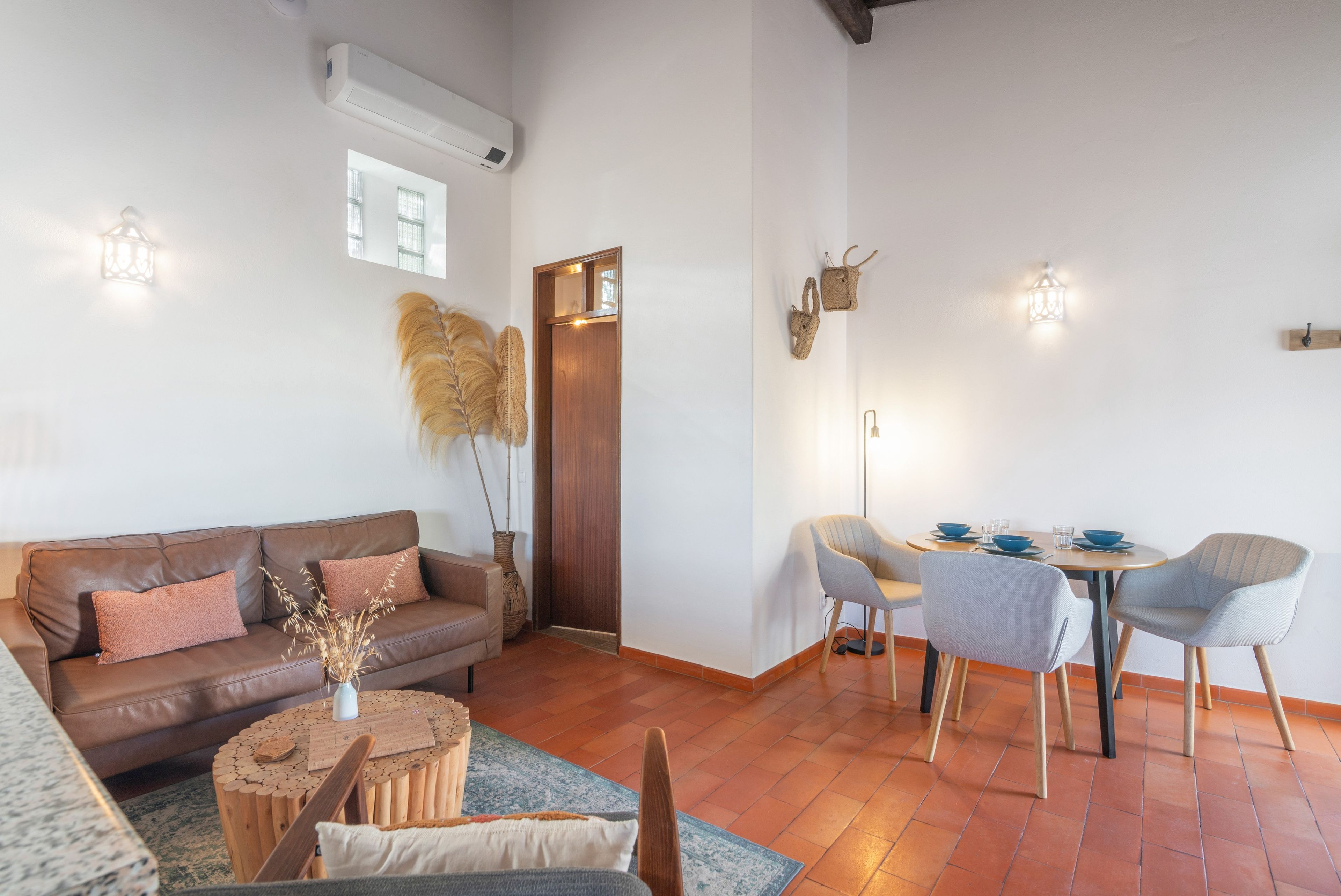 Un espace de vie moderne avec un canapé en cuir marron, une table basse en bois et un coin repas comprenant deux chaises et une table.