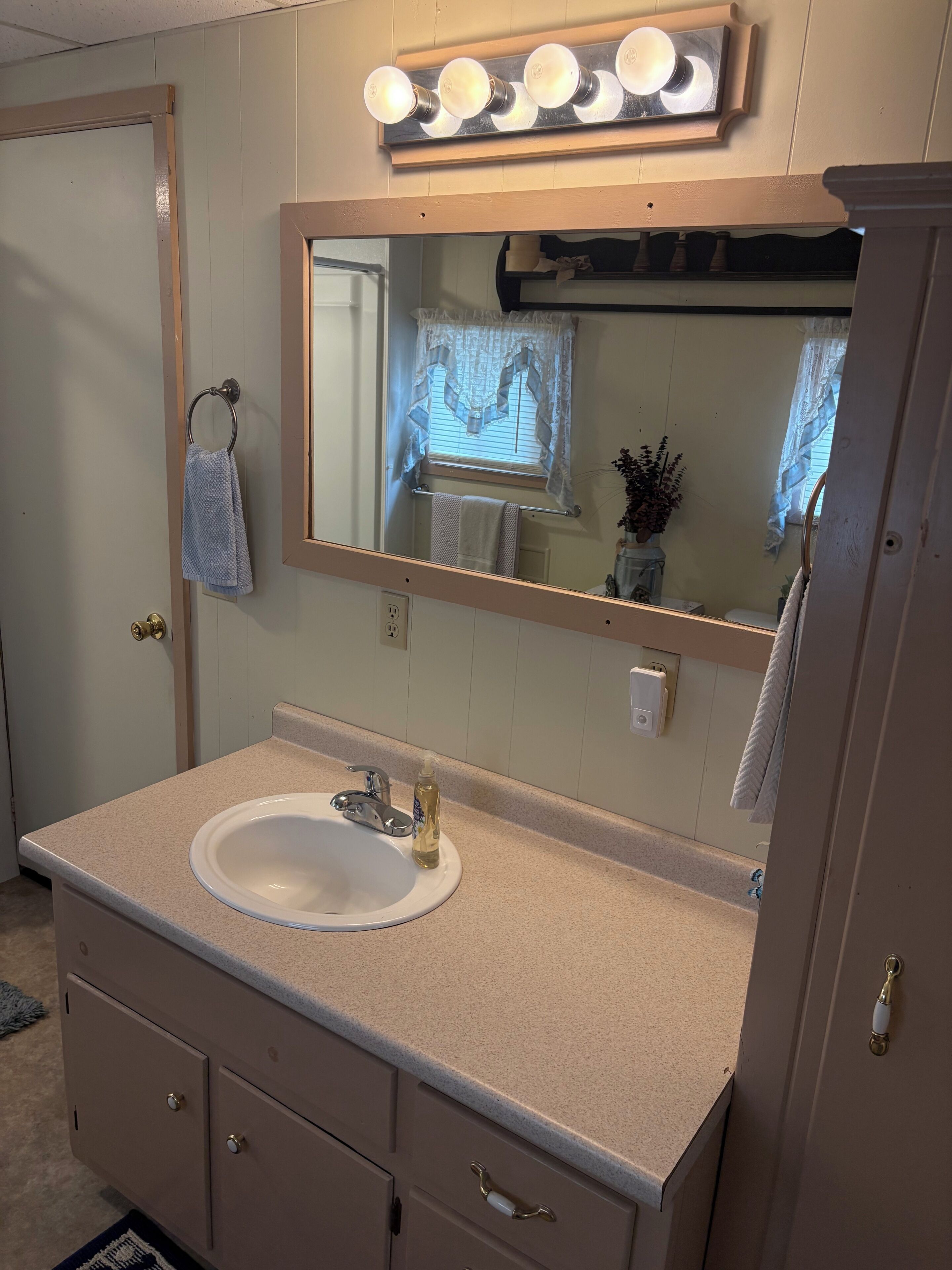 Un bagno con lavandino, specchio, mobile lavabo e porta asciugamani.