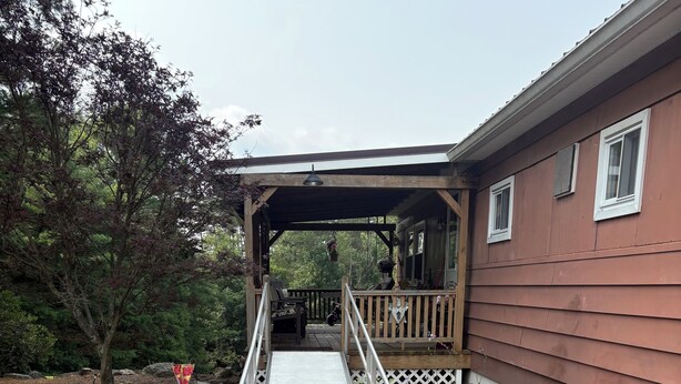 Un espace extérieur abrité, doté d’une terrasse en bois qui mène à un bâtiment.