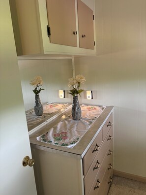 Una cocina con un refrigerador, dos jarrones con flores y una encimera con mantel floreado.